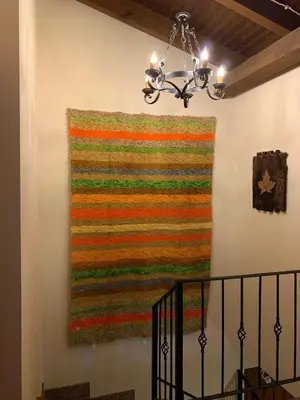 a colorful rug hanging on a wall with a chandelier at Estrella del alba in Villarino de Sanabria