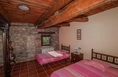 a bedroom with two beds and a stone wall at Mirador de Babia in Huergas