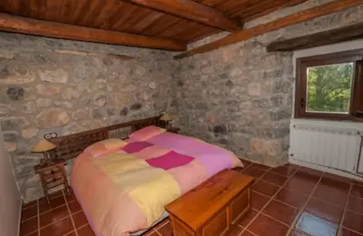 a bedroom with a bed in a stone wall at Mirador de Babia in Huergas