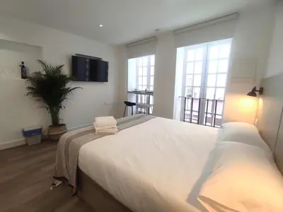 a large white bed in a room with windows at L1 - Disfruta en Os Vinos a dos pasos de la catedral in Ourense