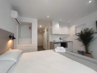 a bedroom with a large white bed and a kitchen at L1 - Disfruta en Os Vinos a dos pasos de la catedral in Ourense