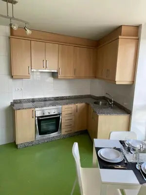 a kitchen with wooden cabinets and a table with chairs at Trailhouse CASTELAO in Sarria