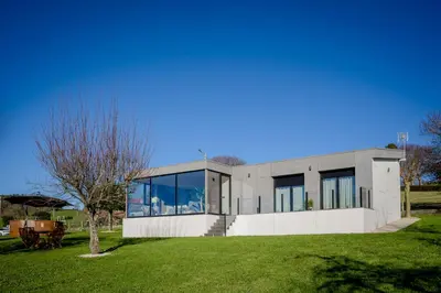 a modern house with large windows and a lawn at Casa Areas in Boimorto