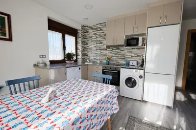 a kitchen with a table and a refrigerator and a washing machine at Casa Melina in Villapedre