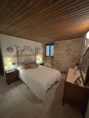 a bedroom with a large bed and a stone wall at Hotel rústico Aldea Figueiredo in Ourense
