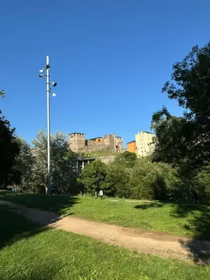 a street light in a park with a castle in the background at Paseo del río in Ponferrada