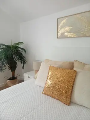 a bed with white sheets and a gold pillow on it at El Naranjo in Padrón