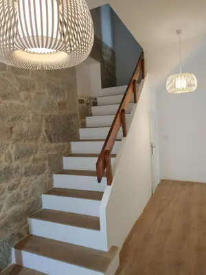a staircase with a stone wall and a chandelier at El Naranjo in Padrón