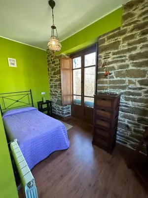 a bedroom with a bed and a stone wall at Apartamentos Helenias in Boal