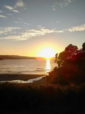 a sunset over the water with the sun setting at The Cliffs - AT Seiramar Sacido in Viveiro