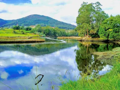 a river with a reflection of the sky in the water at The Cliffs - AT Seiramar Area in Viveiro