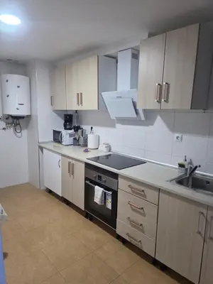 a kitchen with white cabinets and a table and a dining room at Casa de sney in Sarria