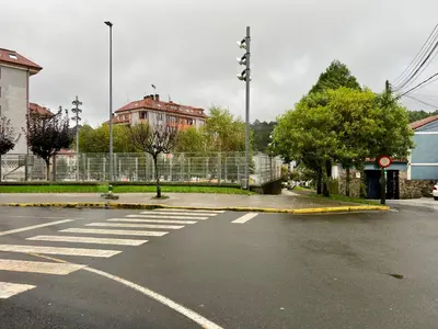 an empty street with a crosswalk in front of a fence at El Marquesado de Santiago en Milladoiro in Milladoiro