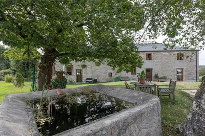 a stone house with a tree and a fountain at Casa Vacacional Retiro Rural en el Camino The Land of Eve in Friol