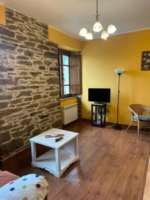a living room with a stone wall and a table at Apartamentos Helenias in Boal