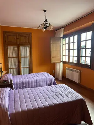 two beds in a bedroom with orange walls and windows at Apartamentos Helenias in Boal