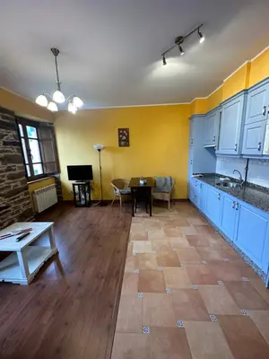 a large kitchen with blue cabinets and a table at Apartamentos Helenias in Boal
