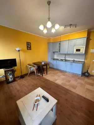 a living room with a table and a kitchen at Apartamentos Helenias in Boal