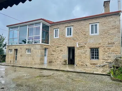 a large stone house with a large window at Rincón rural in Tomonde
