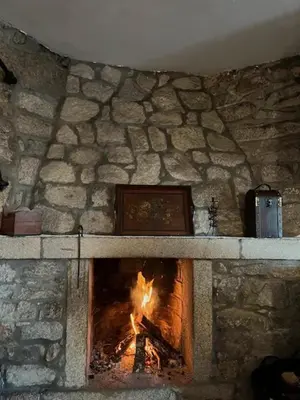 a stone fireplace with a fire in it at Rincón rural in Tomonde
