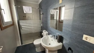 a bathroom with a sink and a toilet and a mirror at A Cuarta Ronda II in Melide