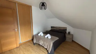 a bedroom with a bed and a wooden door at A Cuarta Ronda II in Melide