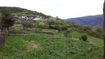 a house on top of a green hill with houses at La Trucha del Arco Iris in El Acebo de San Miguel
