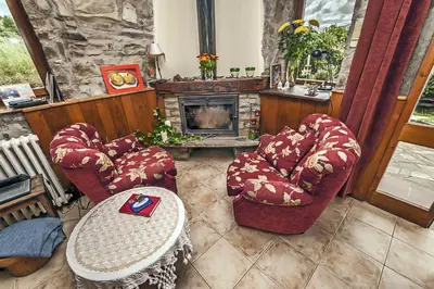 a living room with two chairs and a fireplace at La Trucha del Arco Iris in El Acebo de San Miguel