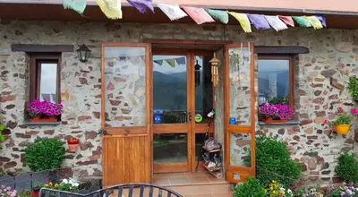 a stone house with a wooden door and flowers at La Trucha del Arco Iris in El Acebo de San Miguel