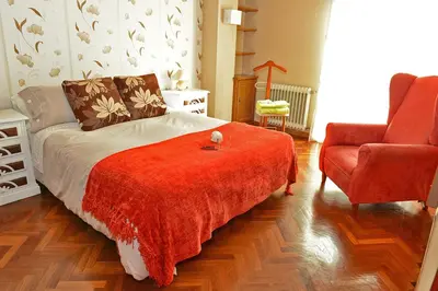 a bedroom with a bed with a red blanket and a chair at Cruxa Apartments garaje incluido in Santiago de Compostela