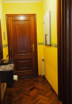 a hallway with a wooden door and yellow walls at Cruxa Apartments garaje incluido in Santiago de Compostela
