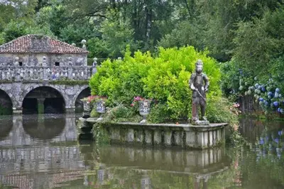 a statue in the middle of a pond in a garden at Cruxa Apartments garaje incluido in Santiago de Compostela