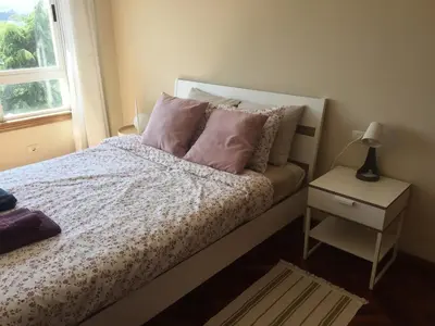 a bedroom with a bed with pink pillows and a window at Apartamento luminoso con vistas a la ría in Cambre