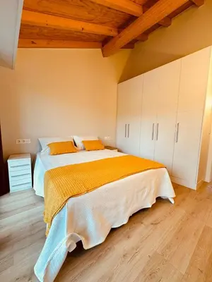 a bedroom with a large bed with white cabinets at Casa a Xanela Azul in Celanova