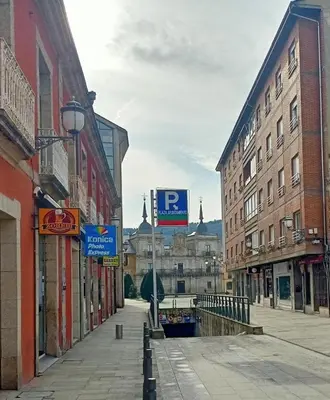 a city street with buildings and a parking sign at APARTAMENTO TURISTICO PLAZA DEL AYUNTAMIENTO in Ponferrada