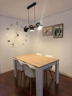 a dining room table with white chairs and a clock on the wall at APARTAMENTO TURISTICO PLAZA DEL AYUNTAMIENTO in Ponferrada