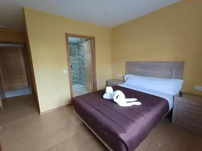 a bedroom with a bed with two stuffed animals on it at Pensión Palomos in San Xoán de Río