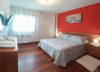 a bedroom with a bed and a red wall at acasadeblanco in Teo