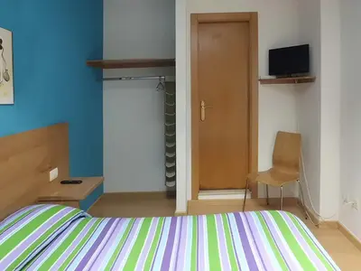 a bedroom with a bed and a door and a chair at Hostal Caracas in Lalín