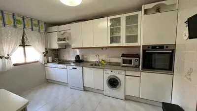 a kitchen with white cabinets and a washing machine at Nice apartment overlooking Ponferrada Castle in Ponferrada