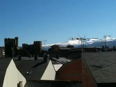 a view of a roof with snow covered mountains in the background at Nice apartment overlooking Ponferrada Castle in Ponferrada