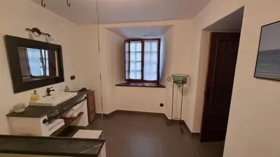 a bathroom with a sink and a mirror and a window at Precioso apartamento con patio centro de Castropol in Castropol