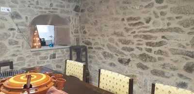 a dining room with a table and a stone wall at Villa Victoria in Teo