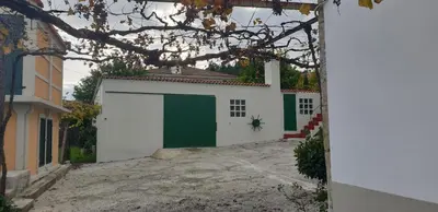 a garage with a green door and a building at Villa Victoria in Teo