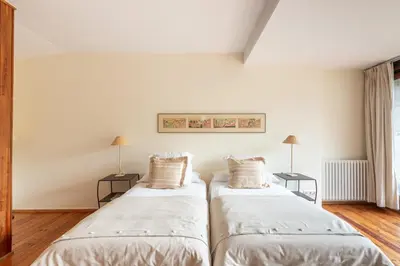 two beds in a room with white walls and wood floors at Casa Doña Blanca, Ourense in San Clodio