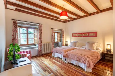 two beds in a bedroom with wooden floors and ceilings at Casa Doña Blanca, Ourense in San Clodio