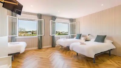 a room with two beds and two windows at Pensión 9 de Abril in O Pedrouzo