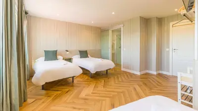 two beds in a room with wooden floors at Pensión 9 de Abril in O Pedrouzo