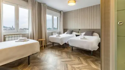 two beds in a hotel room with windows at Pensión 9 de Abril in O Pedrouzo