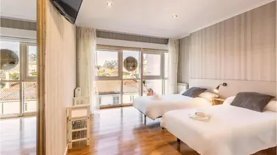 a hotel room with two beds and a balcony at Pensión 9 de Abril in O Pedrouzo